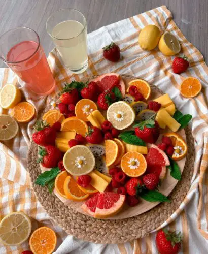 An overview of the lemonade inspired fruit board with 2 cups of lemonade next to it.