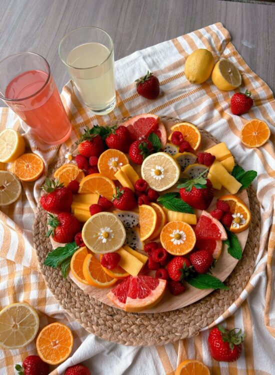 An overview of the lemonade inspired fruit board with 2 cups of lemonade next to it.